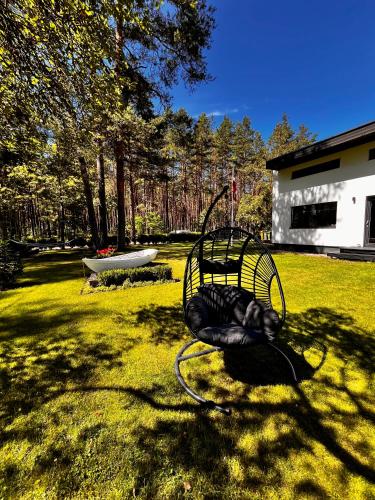 a chair sitting in the grass in a yard at Villa Gauja - holiday home close to the sea and lake in Gauja