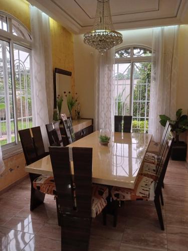 a dining room with a table and chairs and a chandelier at Duplex meublé 5 chambres, piscine, ménagère, voiture à louer Douala Yassa - Tigson in Douala
