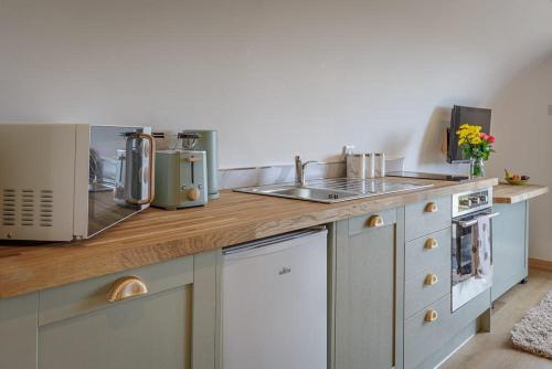 a kitchen counter with a sink and a microwave at The Galloway Steading -The Hedgehog's Hideout family cabin with Hot Tub and Fire Pit in Glenluce