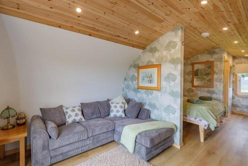 a living room with a couch and a bed at The Galloway Steading -The Hedgehog's Hideout family cabin with Hot Tub and Fire Pit in Glenluce