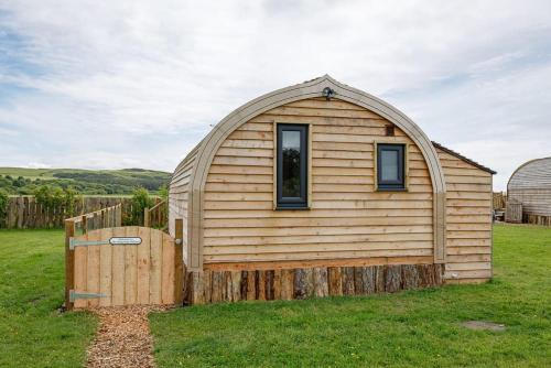 a small wooden house in a field of grass at The Galloway Steading -The Hedgehog's Hideout family cabin with Hot Tub and Fire Pit in Glenluce