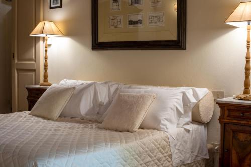 a bedroom with a bed with white sheets and two lamps at La Locanda di Villa Toscana in Bibbona