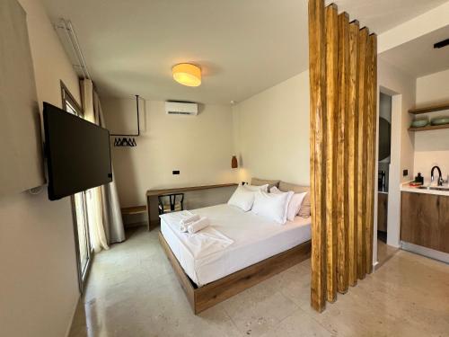 a bedroom with a bed with white sheets and a television at Gioma Garden Villas in Istron