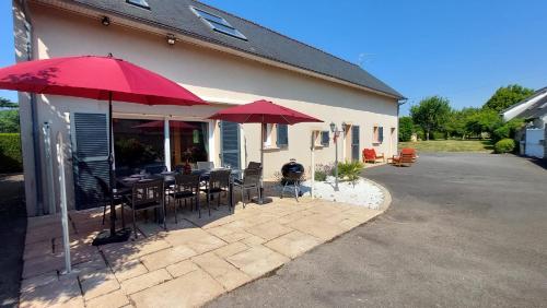 a patio with tables and chairs and umbrellas at Le So Art, grande maison 4 chambres, terrain de pétanque, grand jardin clos, flipper, babyfoot, jeux Arcade, ping pong,1 km mer, proche golf, Port en Bessin, Bayeux et plages du débarquement, adaptée enfants in Commes
