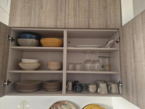 un meuble de cuisine rempli de vaisselle et d'assiettes dans l'établissement Appartement Marine - Park Avenue- Wifi-Jardin-Pkg, à La Rochelle