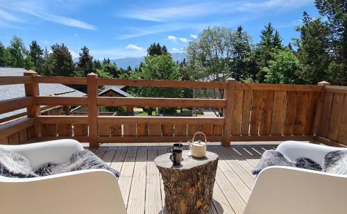 une terrasse avec des chaises blanches et une clôture en bois dans l'établissement Chalets Collection Cachemire - Les Chalets Secrets, à Bolquère-Pyrénées 2000