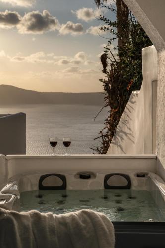 two glasses of wine in a jacuzzi tub with the ocean at Mill Houses New Elegant Suites in Firostefani
