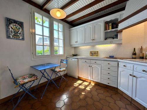 une cuisine avec des armoires blanches et une table et des chaises dans l'établissement 764 - Belle maison de caractère pour 8 voyageurs, à Erquy