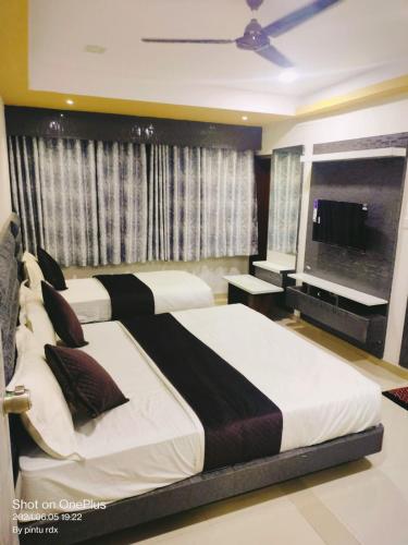 a bedroom with two beds and a flat screen tv at Hotel Mewad Inn in Vadodara