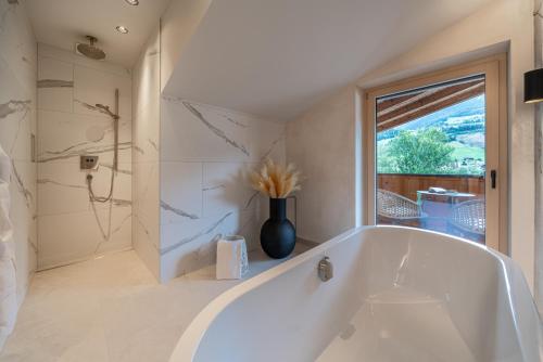 a white tub in a bathroom with a window at Hotel Post in Kaltenbach