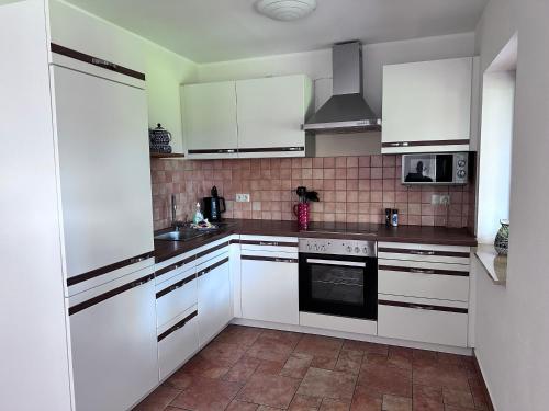 Una cocina con gabinetes blancos y un horno de estufa. en Landhäuschen Danneborth, en Danneborth