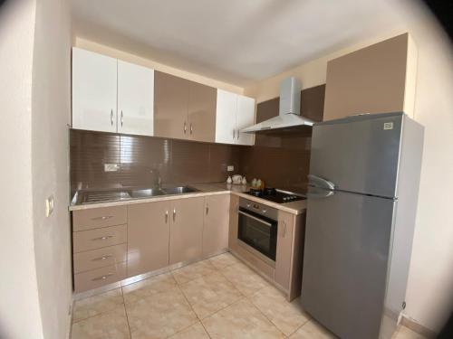 una cucina con armadi bianchi e frigorifero in acciaio inossidabile di Village house a Shkodër