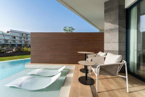 a pool with two chairs and a table next to a pool at Barceló Playa Blanca in Playa Blanca