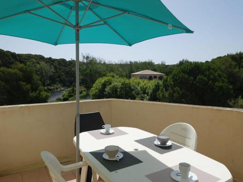 - une table avec un parasol vert sur le balcon dans l'établissement Apartment Les Rivages de Coudoulière-28 by Interhome, à Six-Fours-les-Plages
