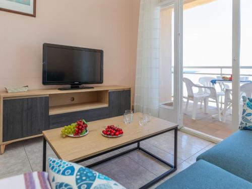 a living room with a tv and a table with fruit at Apartment Fénix Marina by Interhome in L'Escala