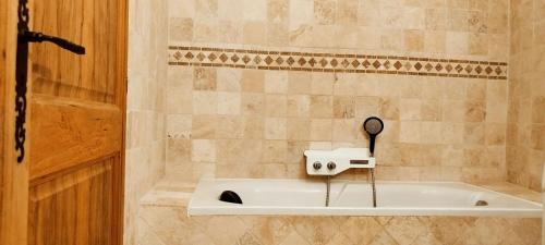 a bathroom with a bath tub with a hair dryer at Appartement charmant près d'Orange avec piscine partagée in Orange