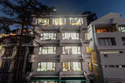 a tall white building with many windows at night at Treebo Maharaja, Near Mall Road in Shimla