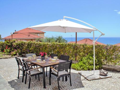 un tavolo con sedie e un ombrellone in un patio di Apartment Annalisa - SLR132 by Interhome a San Lorenzo al Mare
