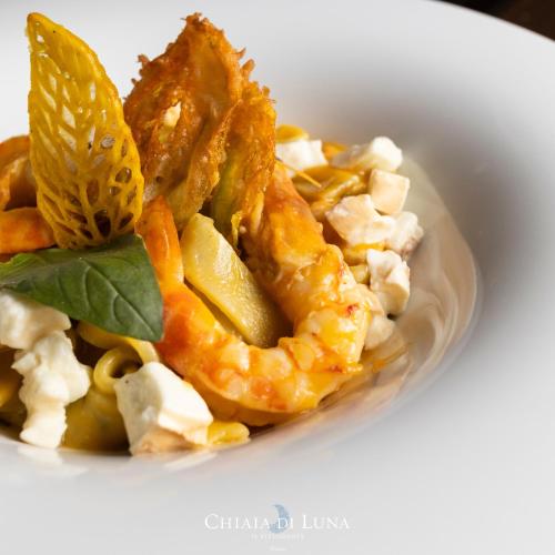 a white bowl of food with shrimp and vegetables at Hotel Chiaia Di Luna in Ponza