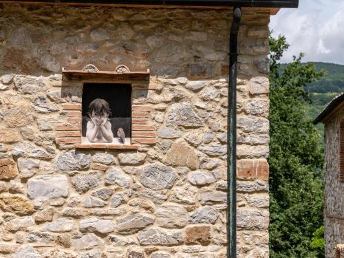 a dog looking out of a window in a stone building at Apartment Arco by Interhome in Travale