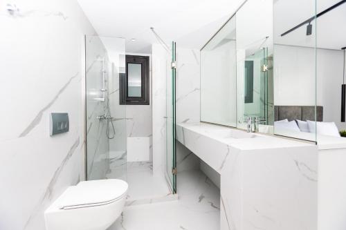 a white bathroom with a toilet and a sink at Varkiza Luxury Suites by Raise in Vari