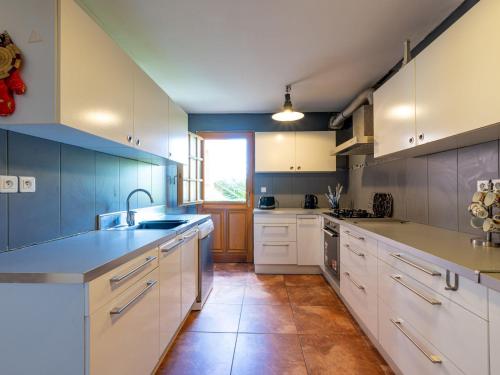 a large kitchen with white cabinets and blue walls at Holiday Home Jasmine by Interhome in Vendres