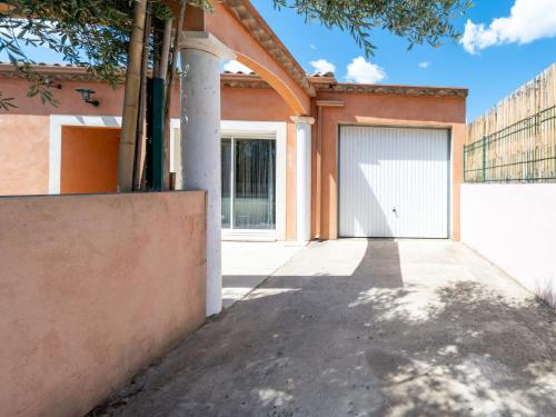 a building with a garage door and a driveway at Holiday Home Jasmine by Interhome in Vendres