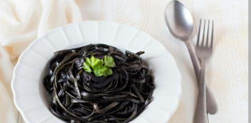 a white plate of pasta with a green plant on it at Hotel Ristorante Antica Marina in Nicotera Marina