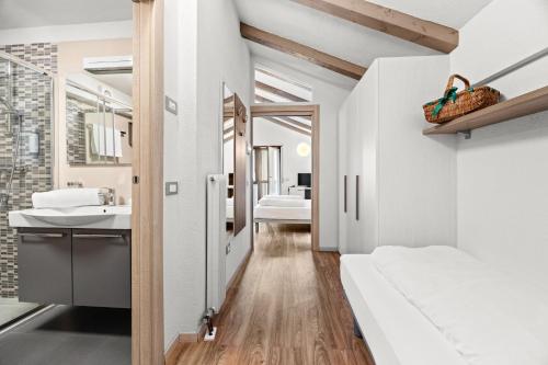 a bathroom with white walls and a white bed and a sink at Aparthotel Des Alpes in Cavalese