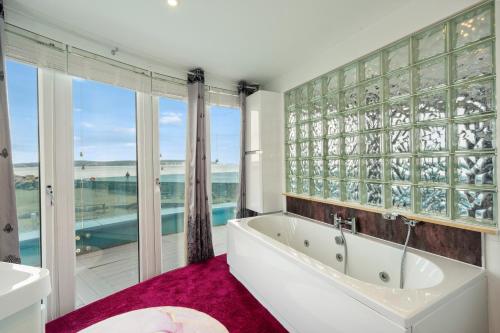 a bathroom with a tub and a large window at Marine House in Lymington