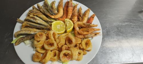 a plate of food with shrimp and a lemon at Hotel Ristorante Antica Marina in Nicotera Marina