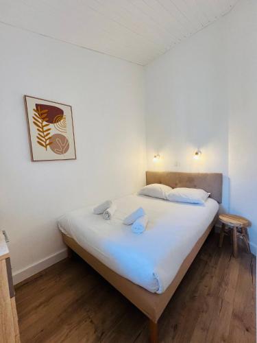 une chambre avec un grand lit avec des draps blancs dans l'établissement Le Baromètre - logement chaleureux, à Talmont-Saint-Hilaire