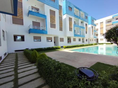 un immeuble d'appartements avec une piscine devant dans l'établissement Apartamento perla del mar, à Martil