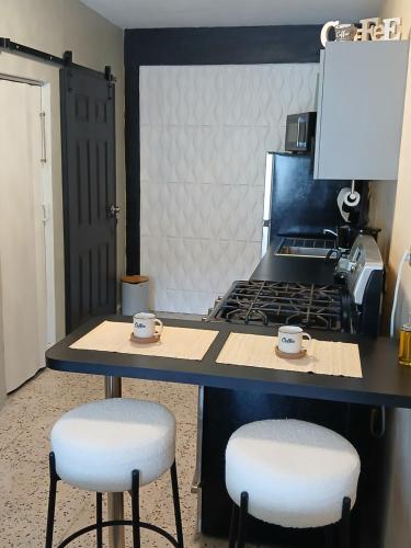 a kitchen with two stools and a table with two cups at Trujillo House Vacation in Trujillo Alto
