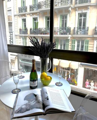 - une table avec un livre, des verres à vin et une fenêtre dans l'établissement Cannes Rue d'Antibes - 2 Minutes walk from Beach, Palais des Festivals, Boulevard de la Croisette - Free Parking - Studio Gray d'Albion, à Cannes