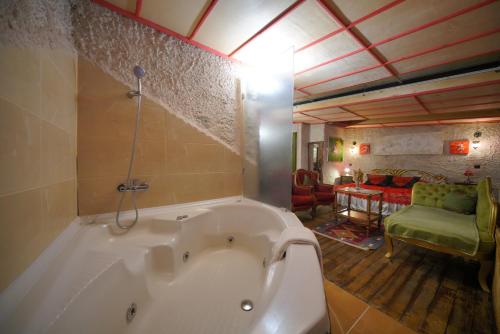 a large white bath tub in a room with a couch at Karlık Evi Hotel - Special Category in Uchisar