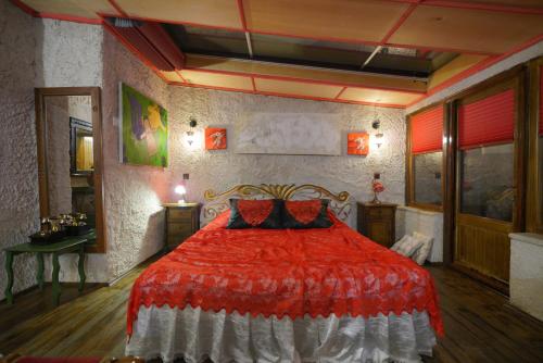 a bedroom with a bed with a red comforter at Karlık Evi Hotel - Special Category in Uchisar
