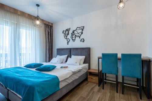 a bedroom with a bed and two blue chairs at Hotel Agape in Zlatibor