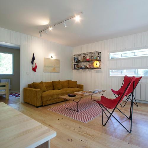a living room with a couch and red chairs at Villa Marina de Talaris, Lacanau in Lacanau
