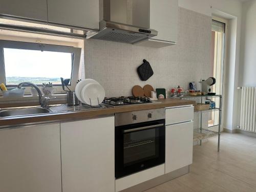 uma cozinha com um lavatório e um fogão forno superior em Attico al Sovrano - Nel cuore della Puglia! em Turi