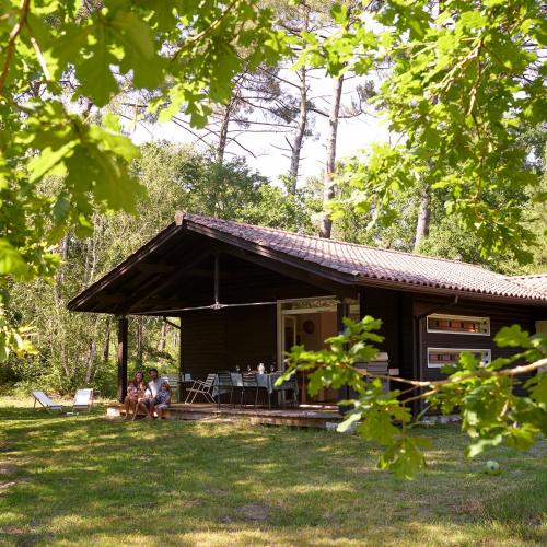 a house with people sitting in front of it at Villa Marina de Talaris, Lacanau in Lacanau