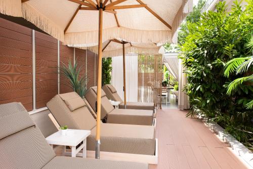 an outdoor patio with chairs and an umbrella at ELLE Rooms & Suites in Paralia Katerinis