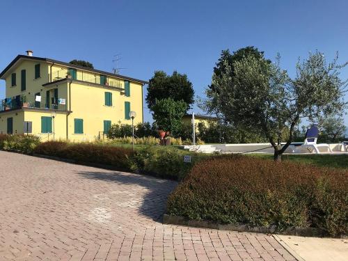 a yellow house with a brick driveway in front of it at Albergo quatro pini in Pozzolengo