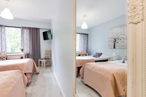 a hotel room with two beds and a mirror at Hotel Pohjankievari in Kempele