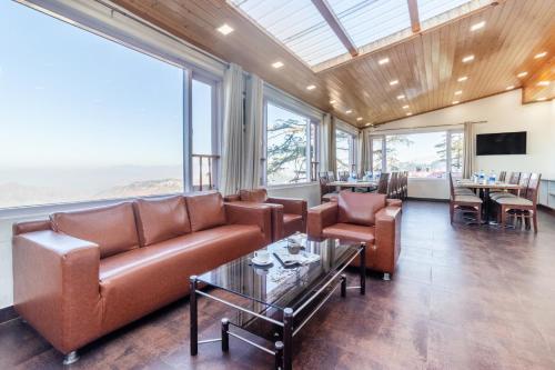 a living room with a couch and tables and windows at Treebo Maharaja, Near Mall Road in Shimla
