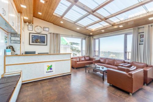 a lobby with a waiting area with leather furniture and windows at Treebo Maharaja, Near Mall Road in Shimla