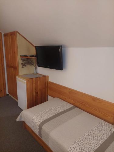 a bedroom with a bed and a flat screen tv on the wall at vila Happy in Veľká Lomnica