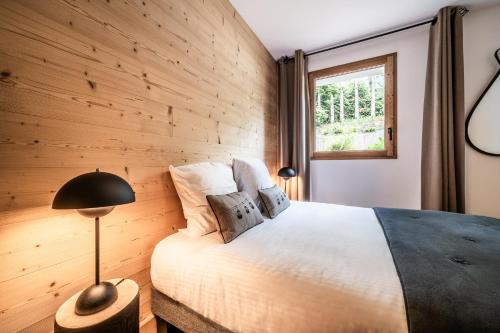 - une chambre avec un lit et un mur en bois dans l'établissement Apartment Lupin Megève - by EMERALD STAY, à Megève