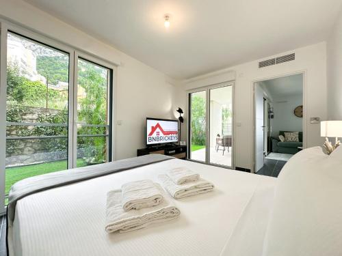 une chambre blanche avec un lit avec deux serviettes dessus dans l'établissement Krystal Garden, Bnbrickeys., à Beausoleil