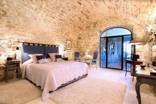 a bedroom with a bed and a stone wall at La Bastide du Tinal in Ménerbes
